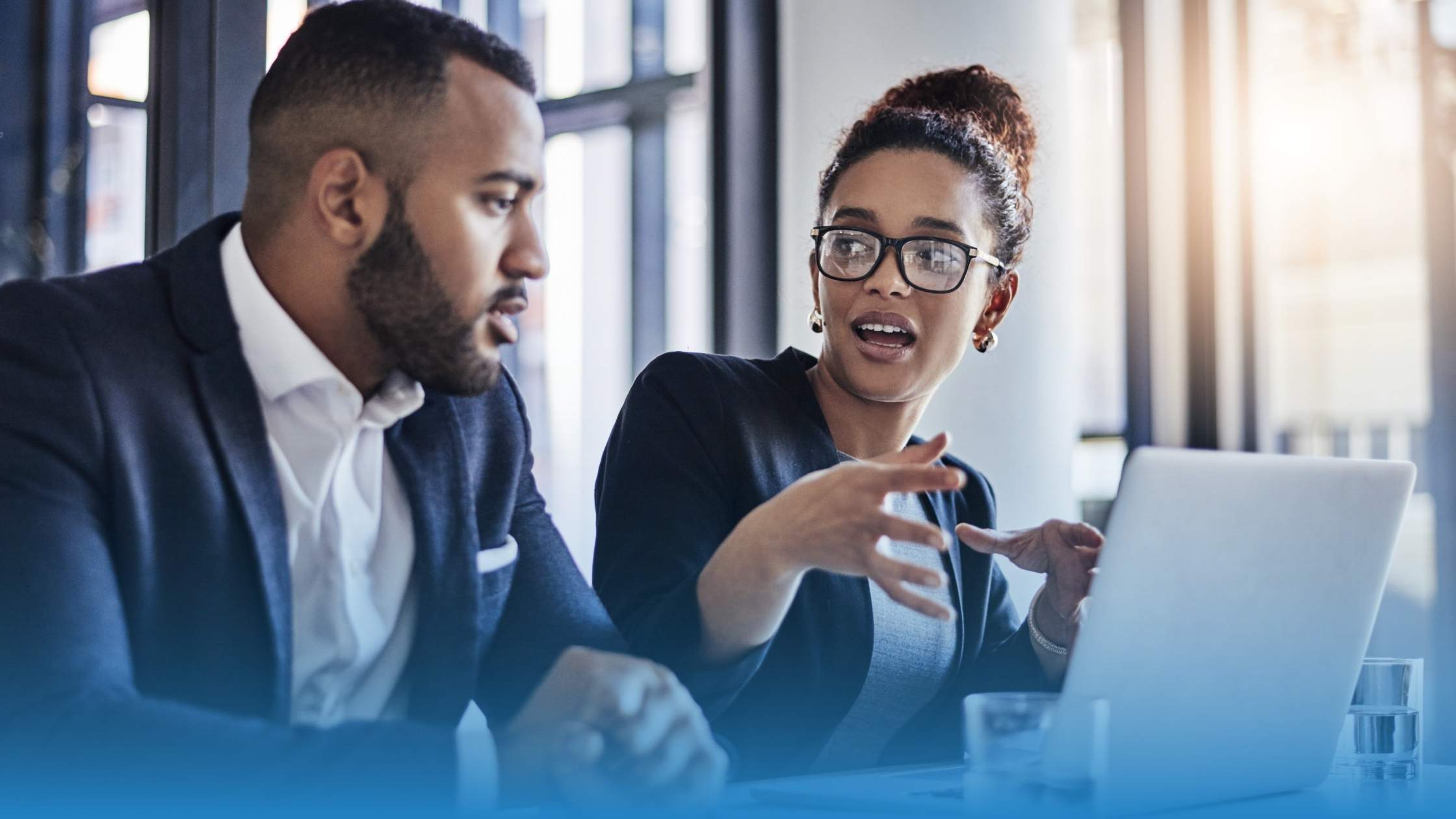 Two legal professionals engaged in a data-driven discussion at a laptop in a modern office, representing the power of legal data intelligence in action.