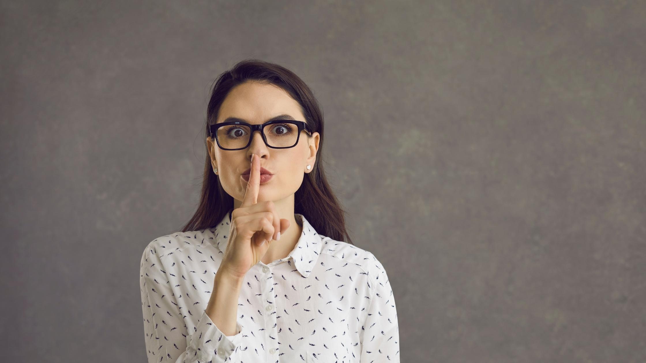 Woman making a “shh” gesture, signaling confidenciality