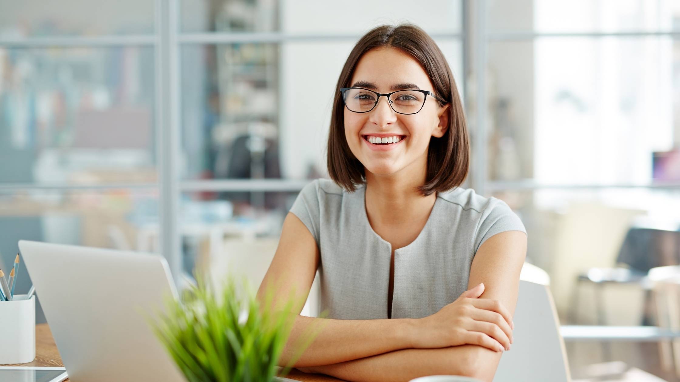 A woman contract expert smiling at a desk, ready to advise on contracts.